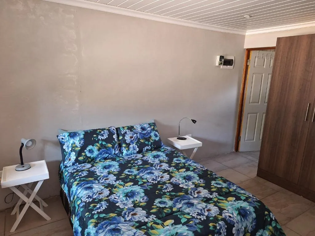 Spacious bedroom with floral bedding, white nightstands, and modern amenities