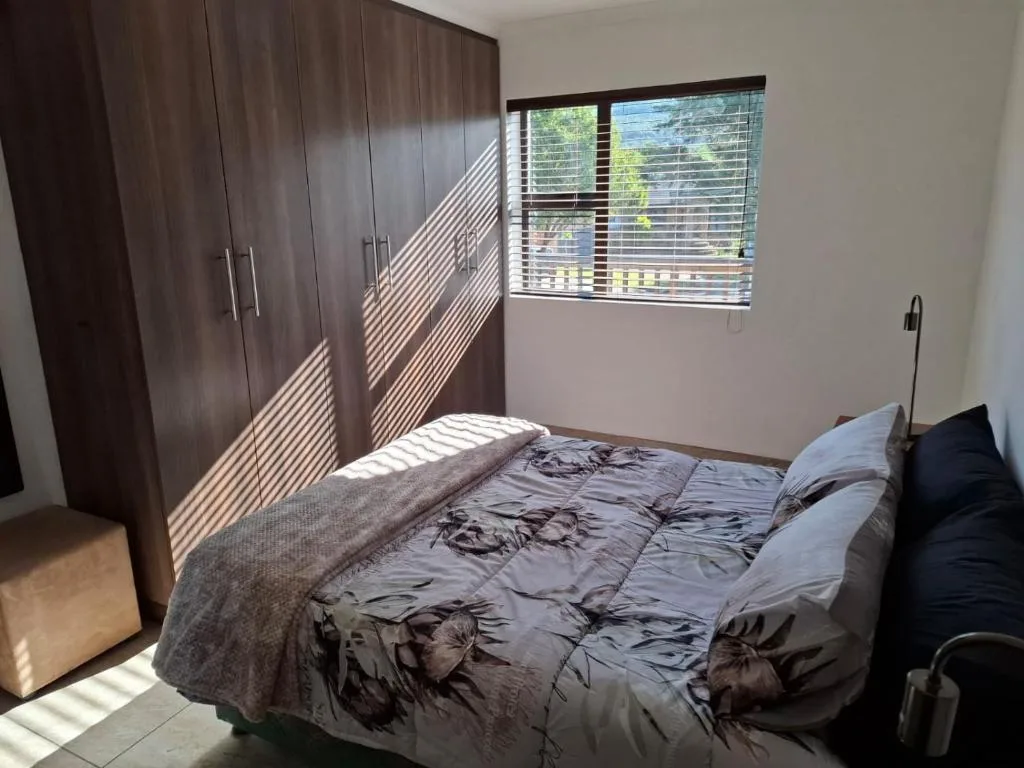 Bright bedroom with double bed, dark wood wardrobe, and large window with views