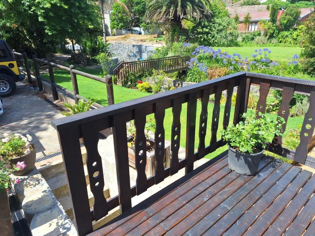 Wooden deck with black railing overlooking manicured garden and lawn