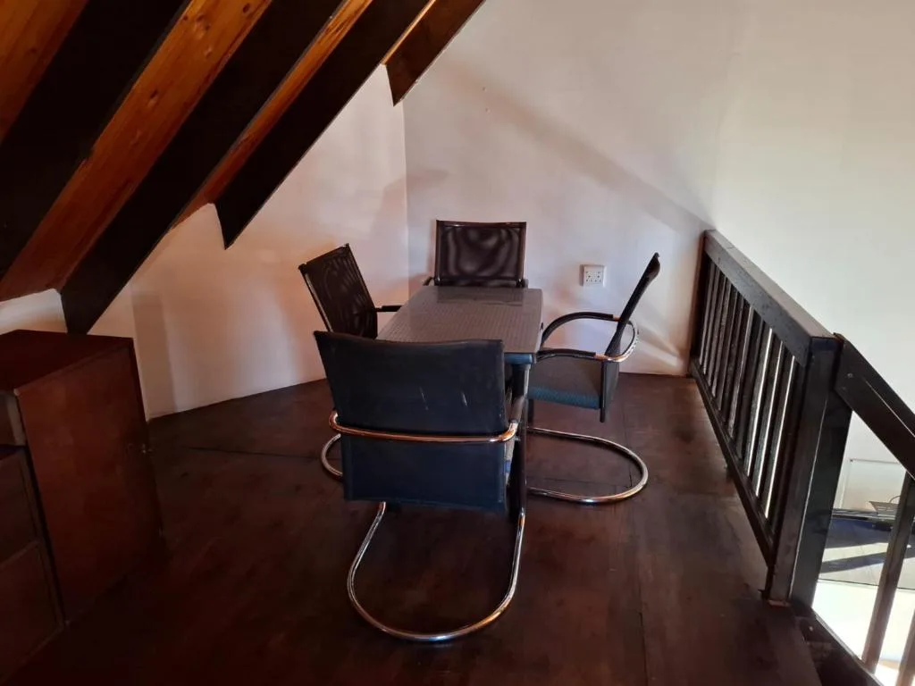 Loft workspace with desk, office chairs, and exposed timber beams