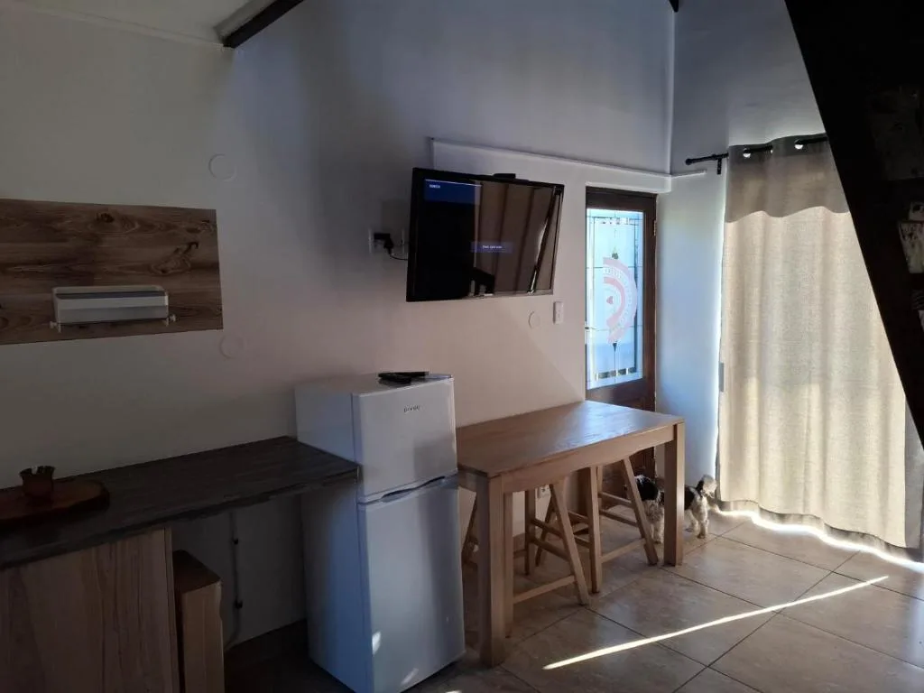 Open-plan kitchen and dining area with white fridge and wooden table