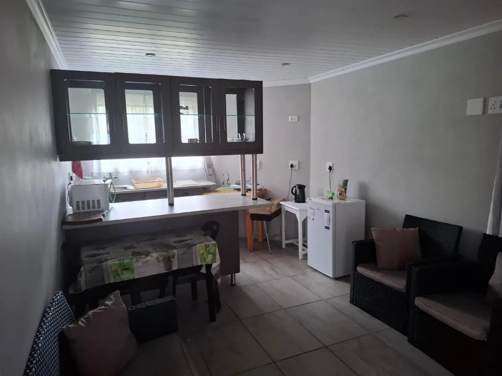 Modern kitchen with black cabinetry, white counters, and dining seating area