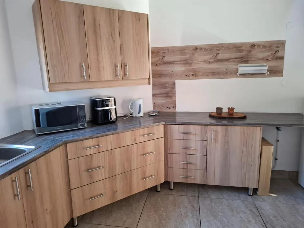 Modern kitchen with wooden cabinetry, dark countertops, and stainless steel appliances