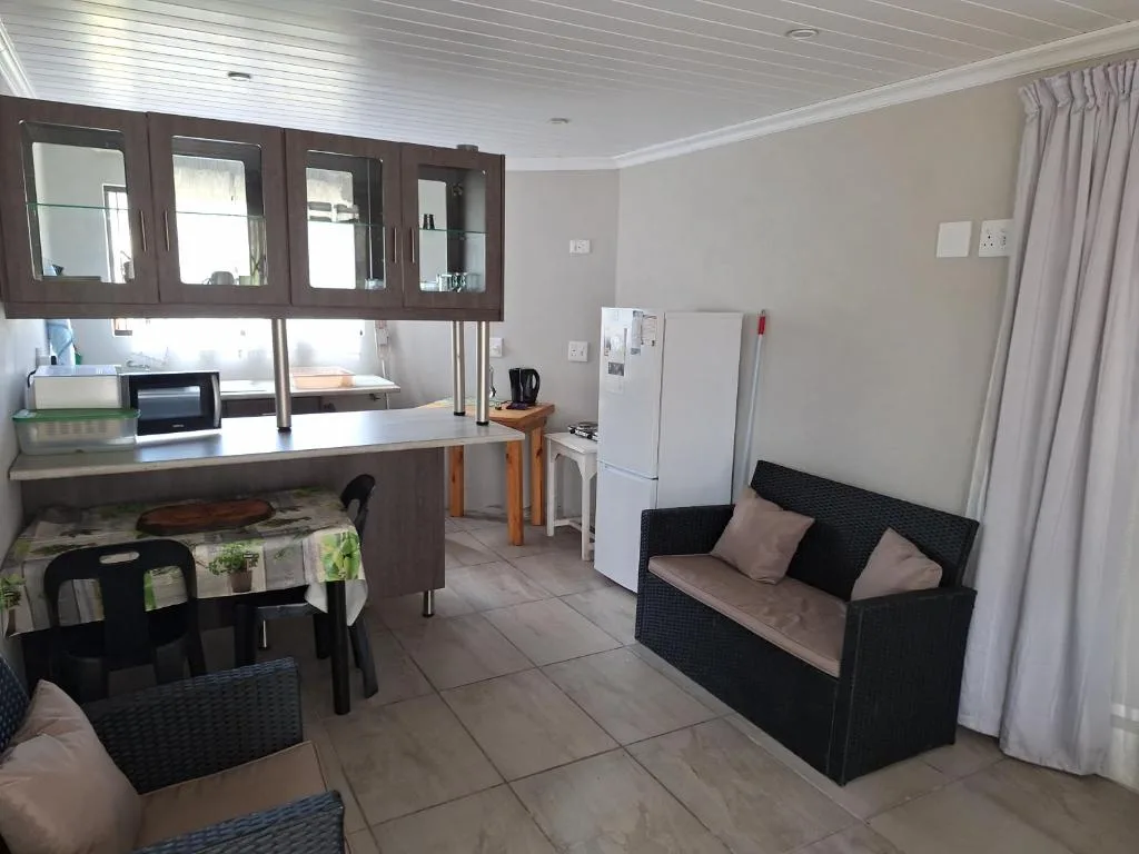 Open-plan lounge and kitchen with black sofa, dining table, and modern cabinetry