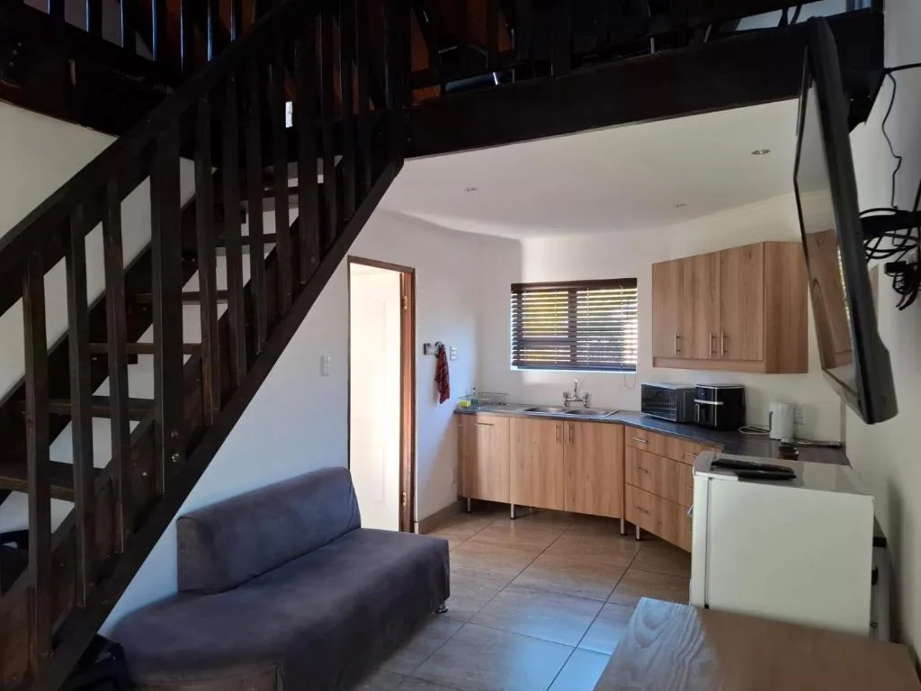 Open-plan lounge and kitchen with wooden stairs and sofa seating