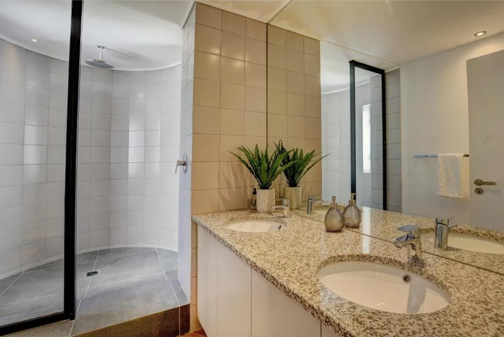 Modern bathroom with dual vanity, rainfall shower, and granite countertops