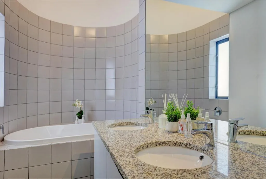 Modern bathroom with dual vanity, granite countertop, and soaking tub