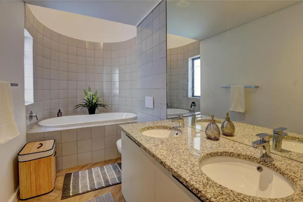 Spacious bathroom with dual vanity, soaking tub, and tiled shower enclosure