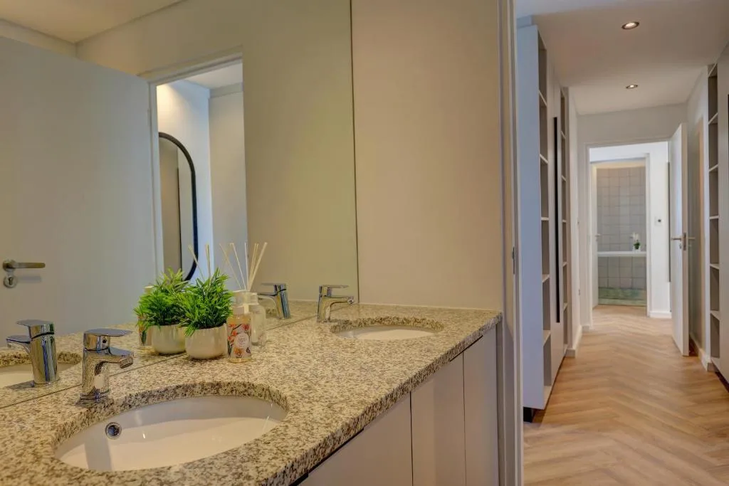 Modern bathroom with double vanity, granite countertop, and decorative plants