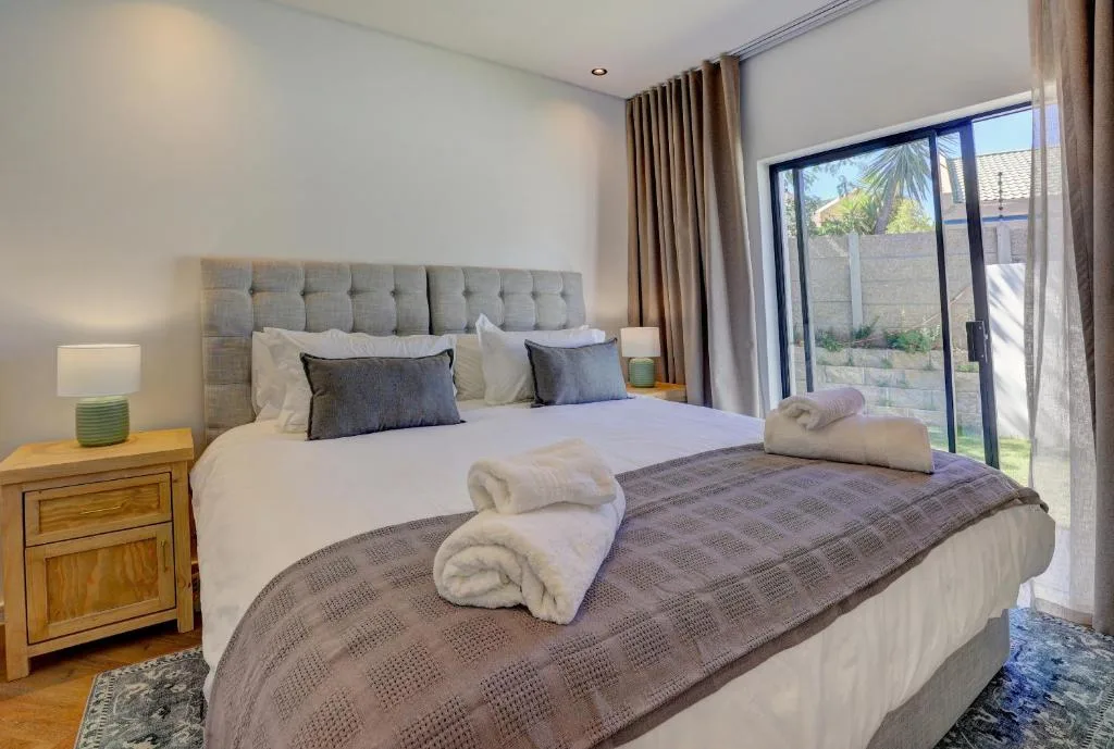 Spacious bedroom with upholstered headboard and garden view doors