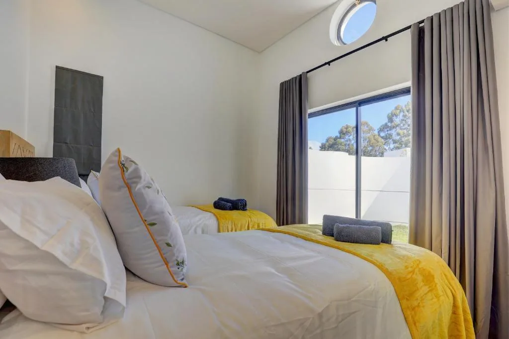 Modern bedroom with white bedding, yellow accent throw, and large sliding glass doors