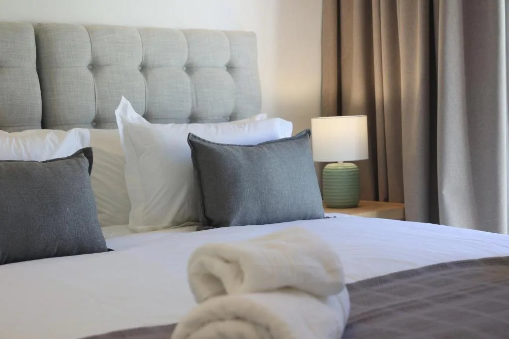 Modern bedroom with upholstered headboard, fresh white linens, and plush pillows