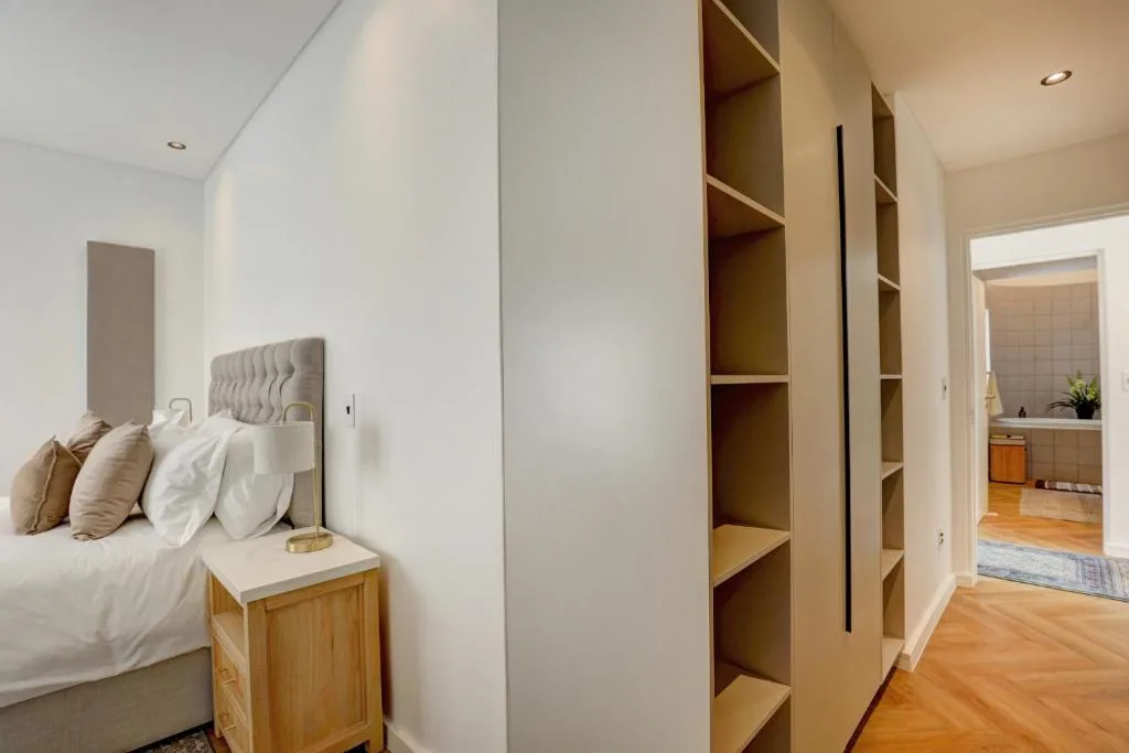 Modern bedroom with built-in wardrobes, bed with neutral pillows, wooden nightstand