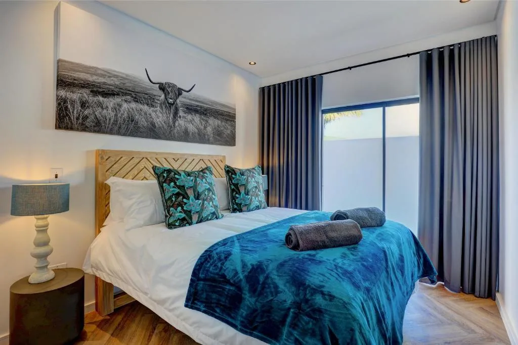 Modern bedroom with wooden headboard, blue bedding, and scenic views