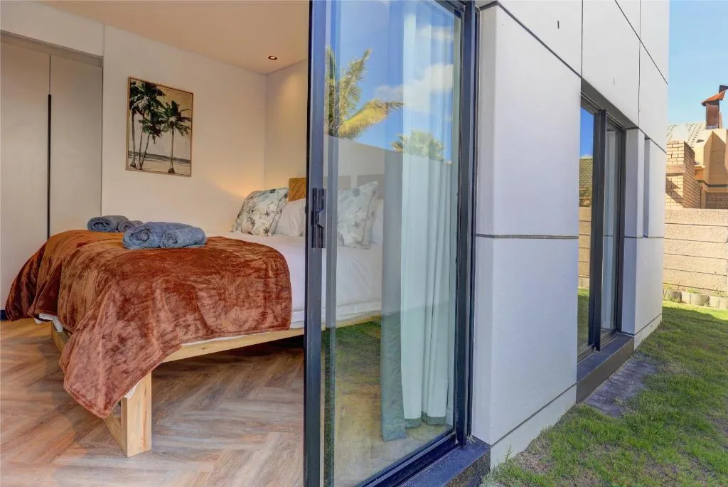 Modern bedroom with rust-colored bedding and garden view through sliding doors