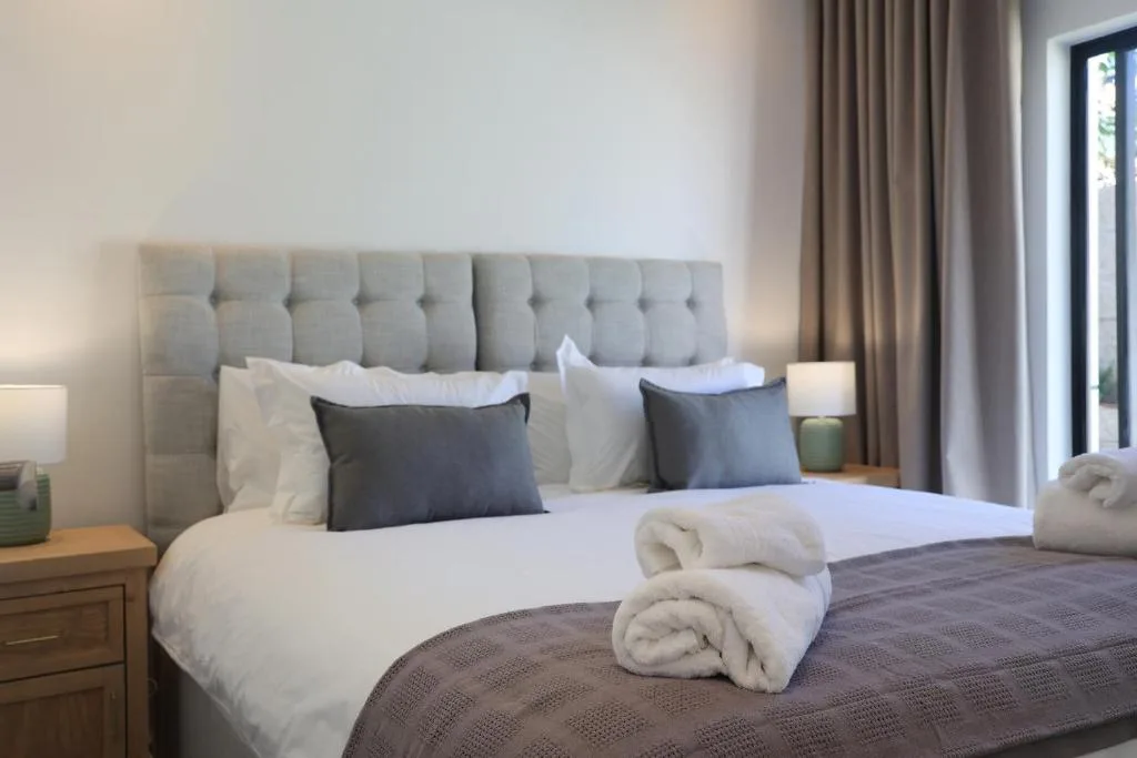 Modern bedroom with gray tufted headboard and white crisp bedding, rolled towels