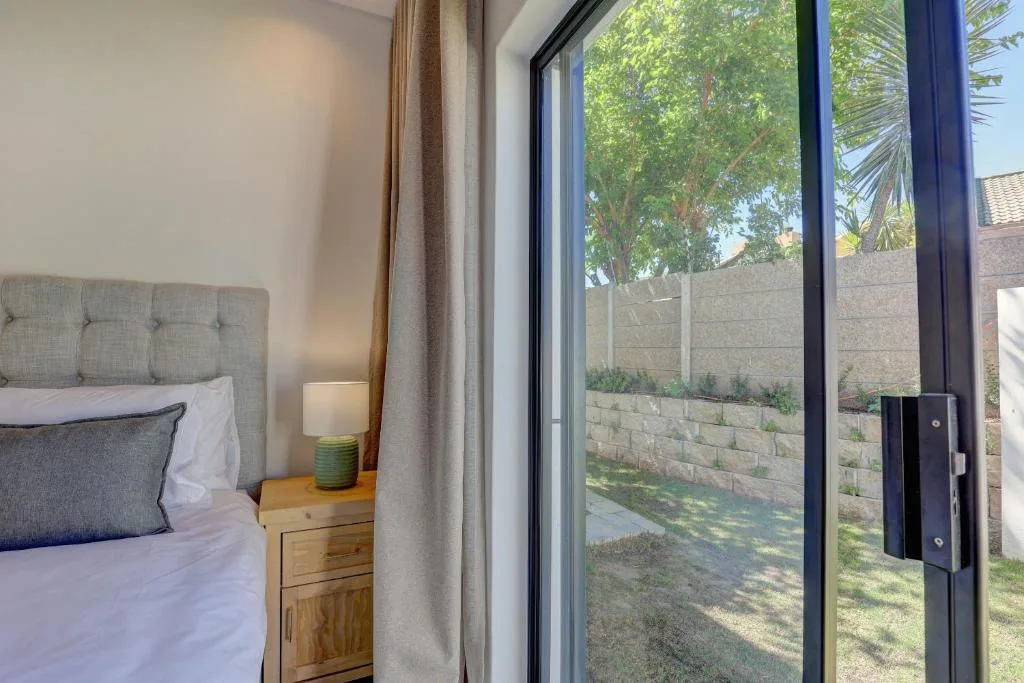 Bright bedroom with gray upholstered headboard and garden view doors