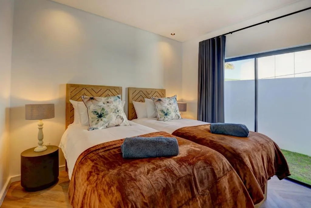 Twin beds with wooden headboards, white linens, brown throw blankets