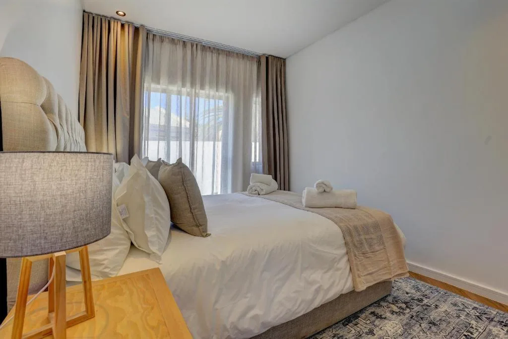 Bright bedroom with queen bed, neutral linens, and floor-to-ceiling windows