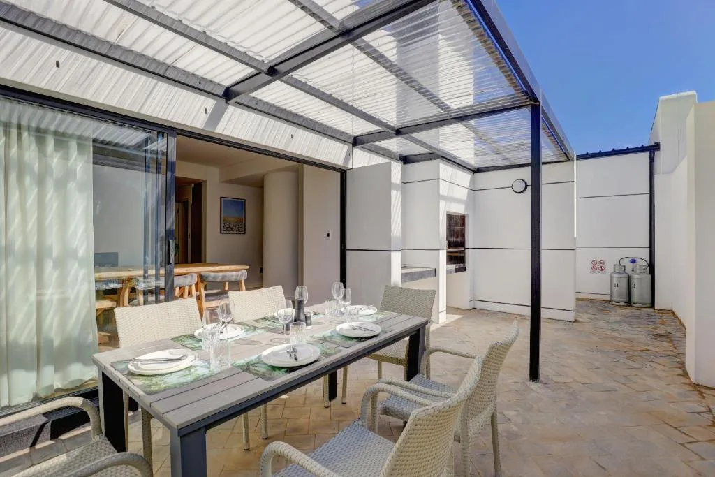 Covered outdoor dining area with set table and wicker chairs