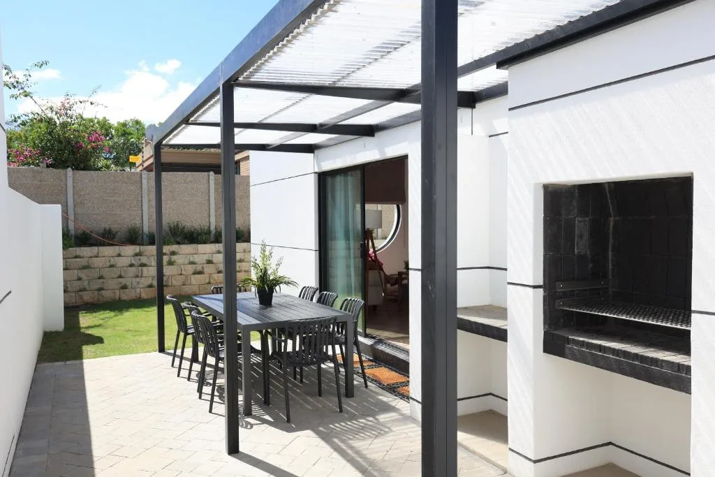 Modern patio with pergola, dining table, and built-in braai area