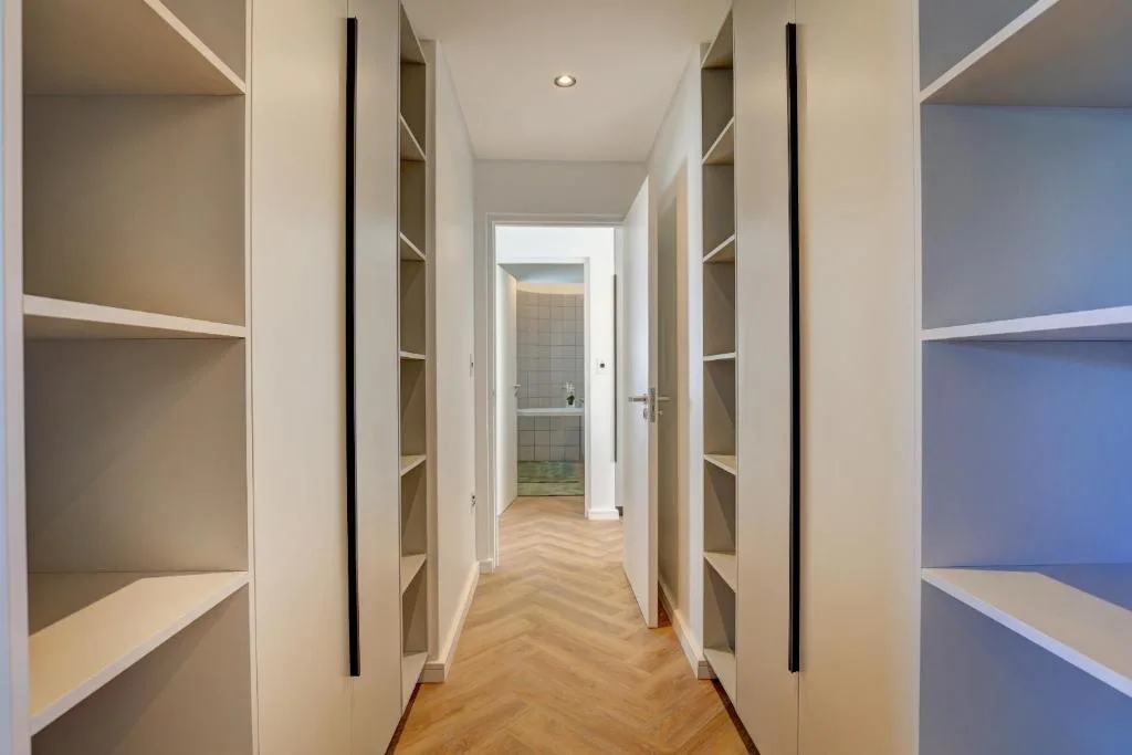 Modern hallway with built-in shelving and herringbone wooden flooring
