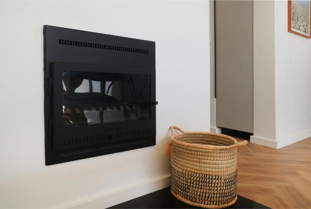 Woven basket beside modern black fireplace insert in lounge