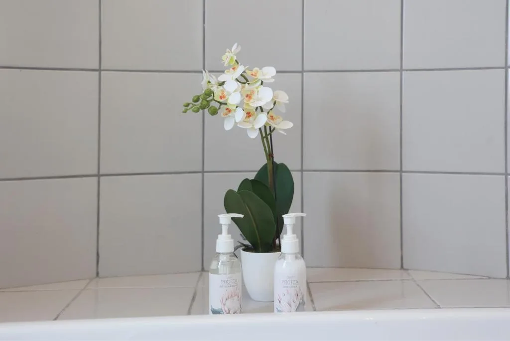 White orchid plant with toiletries on bathroom shelf