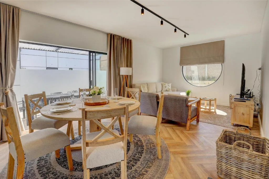 Open-plan dining area with round wooden table and chairs overlooking deck