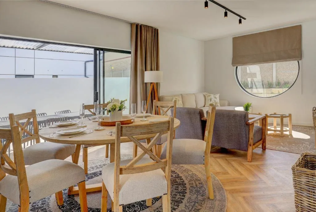 Modern dining area with wooden table, neutral chairs, and open-plan lounge view