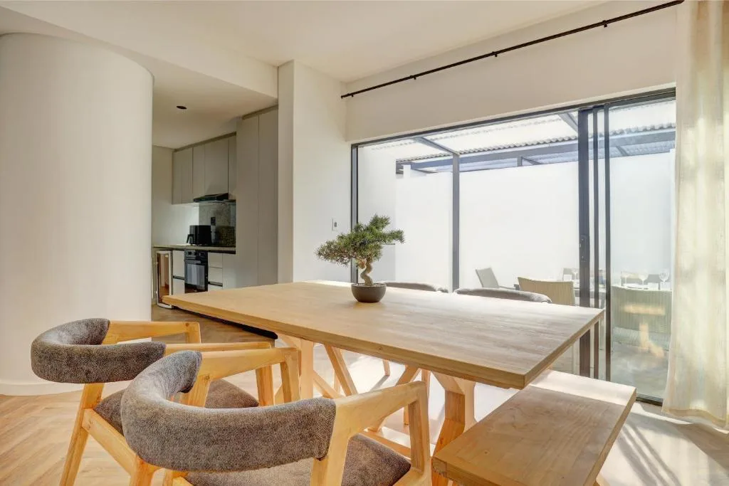 Modern dining table with wooden chairs overlooking deck and garden