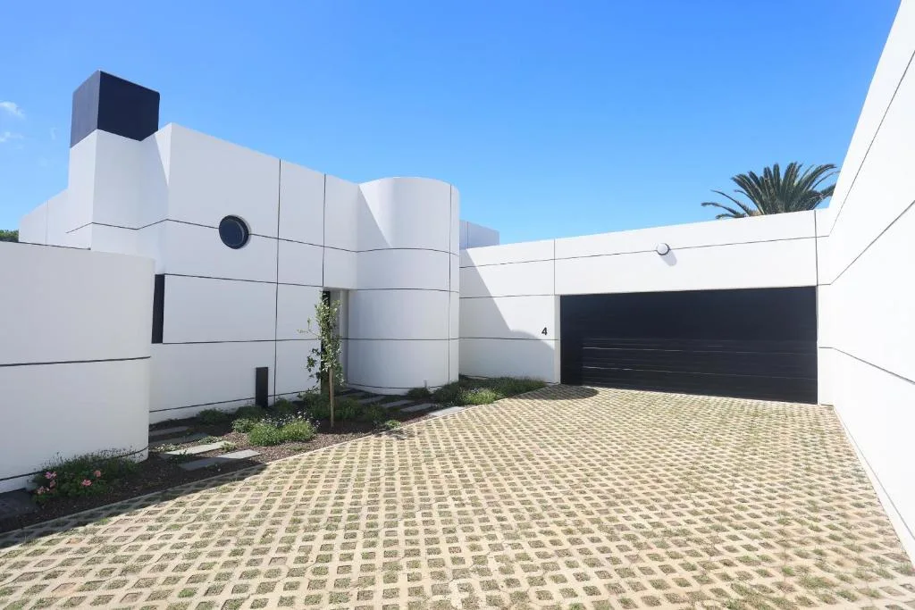 Modern white building facade with black garage door and paved driveway