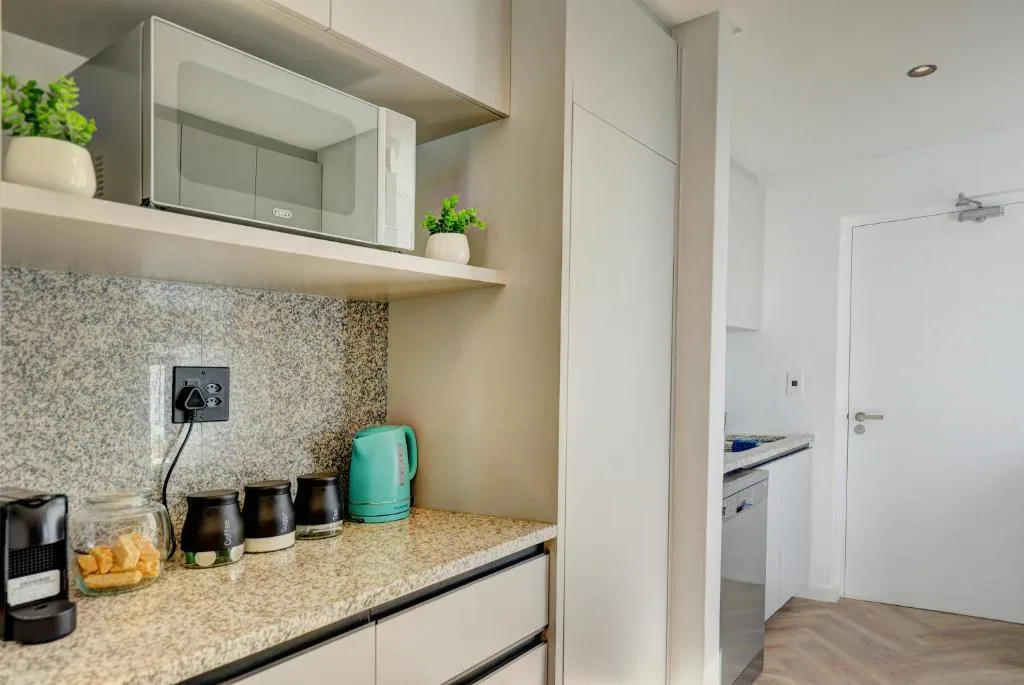 Modern kitchen with granite countertop, built-in appliances, and turquoise kettle