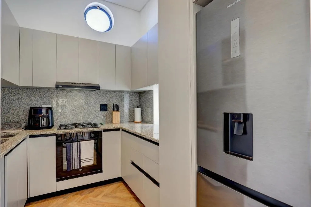 Modern kitchen with cream cabinetry, granite countertop, and stainless steel appliances