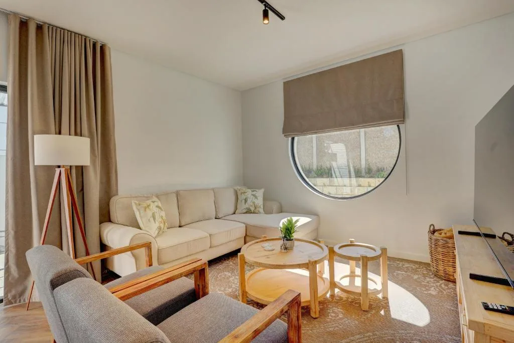 Bright lounge with cream sofa, wooden chairs, and round coffee table