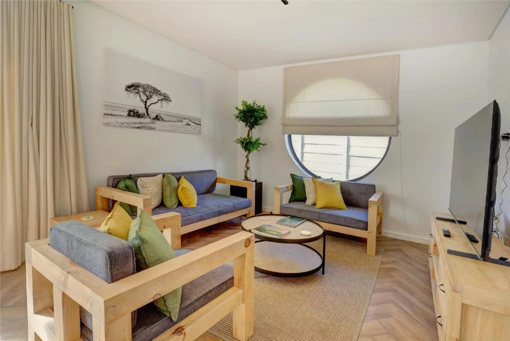 Modern lounge with multiple wooden-framed sofas and colorful cushions, round coffee table