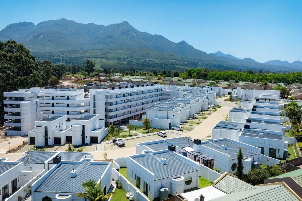 Dramatic mountain backdrop behind modern white residential complex with solar panels