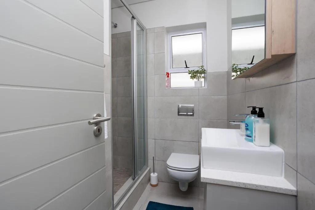 Modern bathroom with shower, toilet, white sink and tiled walls
