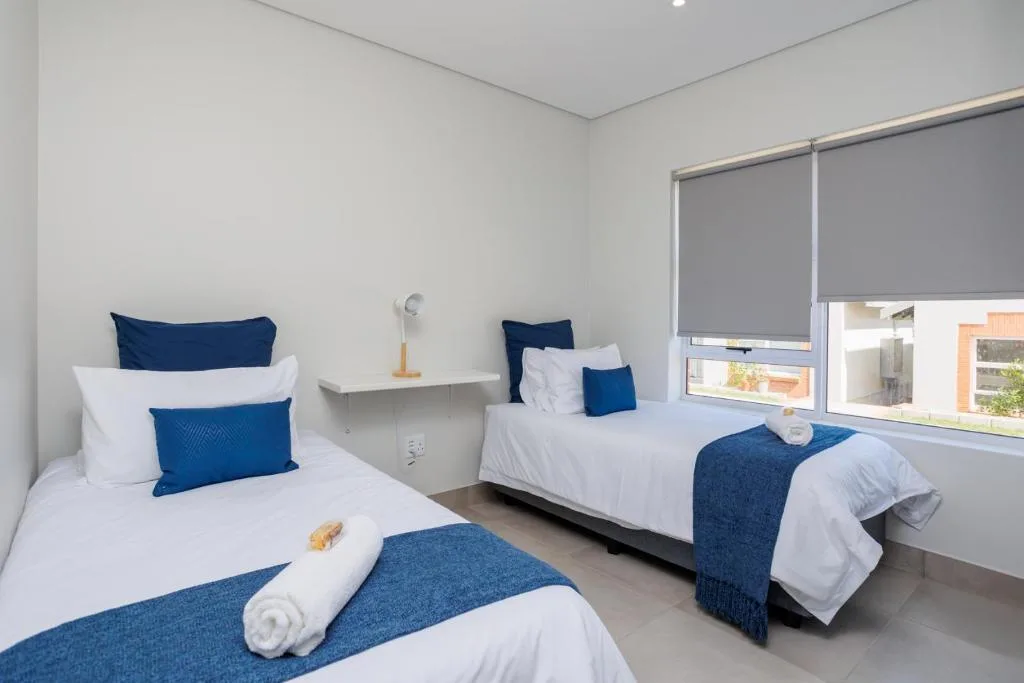 Bright bedroom with two twin beds, blue pillows, and modern furnishings