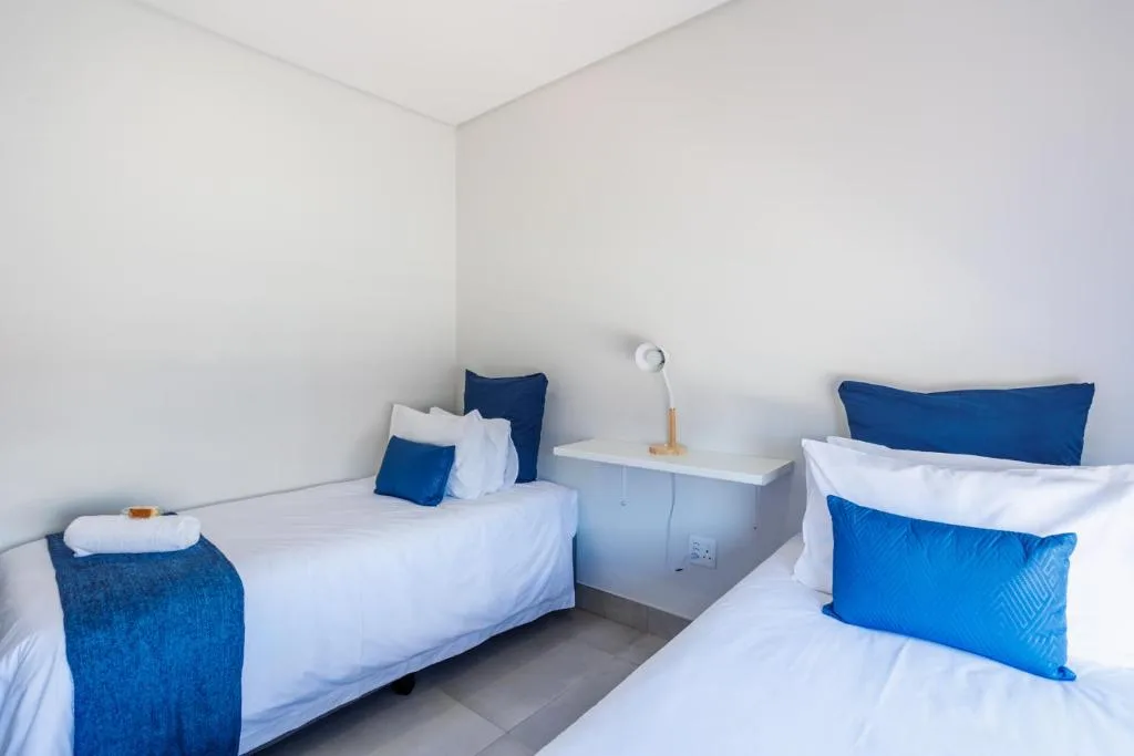 Clean twin bedroom with white linens and blue accent pillows