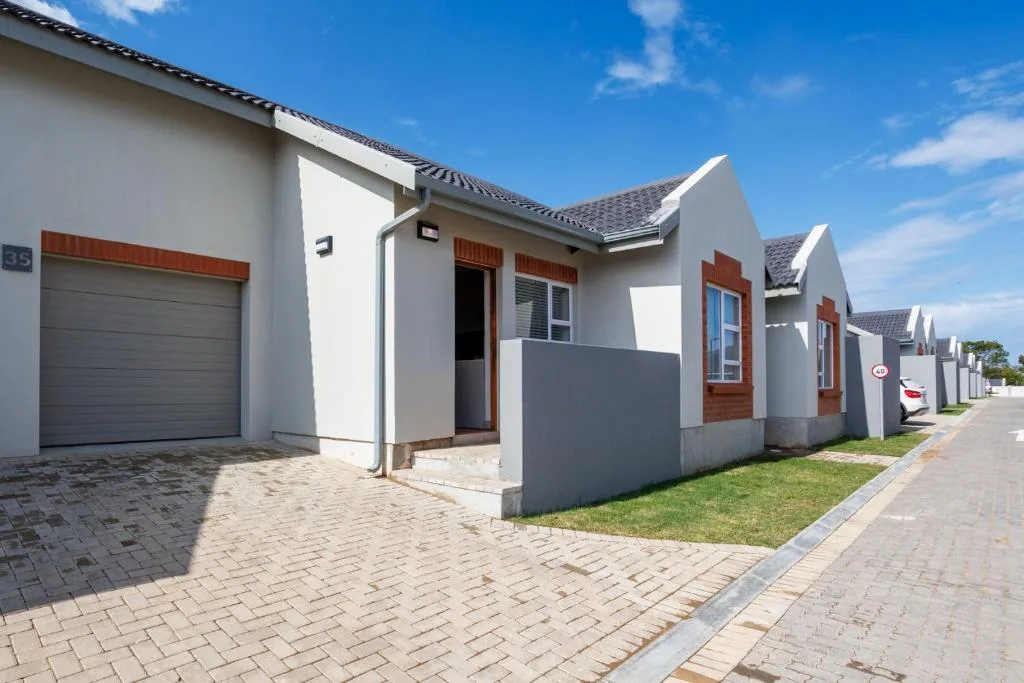 Modern white townhouse with garage and wooden accents along a tree-lined street