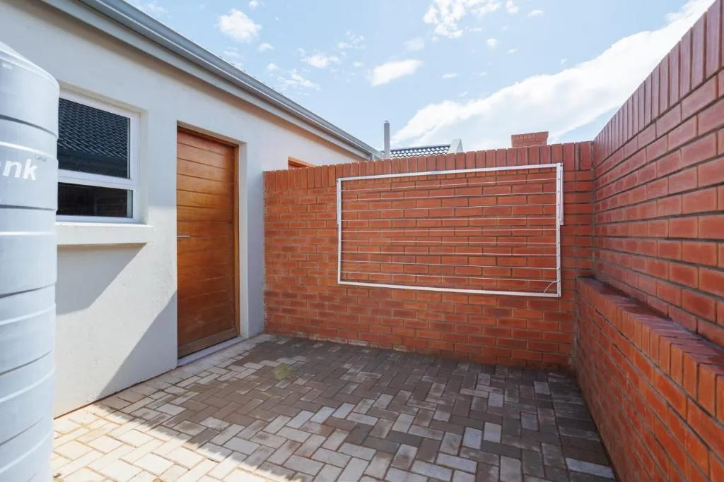 Modern townhouse entrance with wooden door and brick paved courtyard