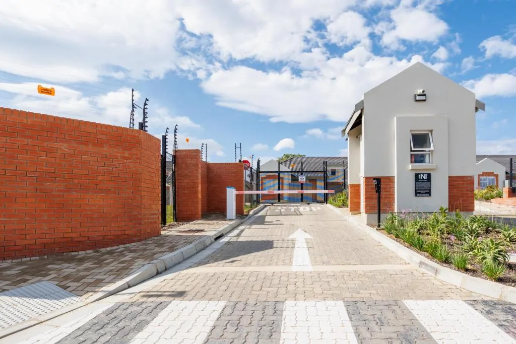 Modern white townhouse with red brick walls and paved entrance driveway