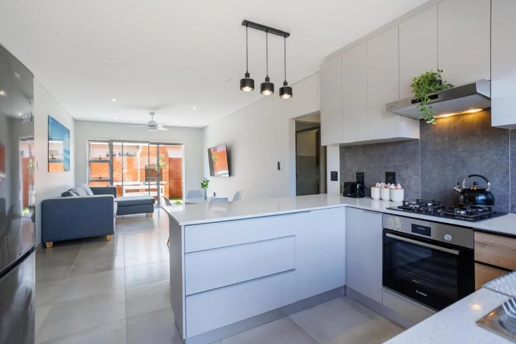 Modern white kitchen with island, gas stove, and pendant lighting fixtures