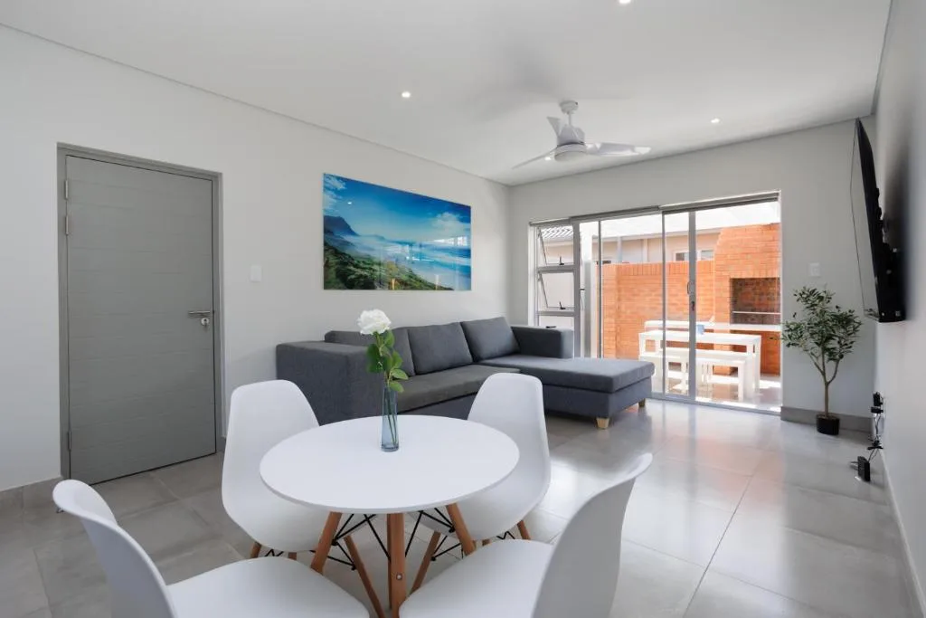 Modern lounge with grey sofa, white dining table, and sliding glass doors