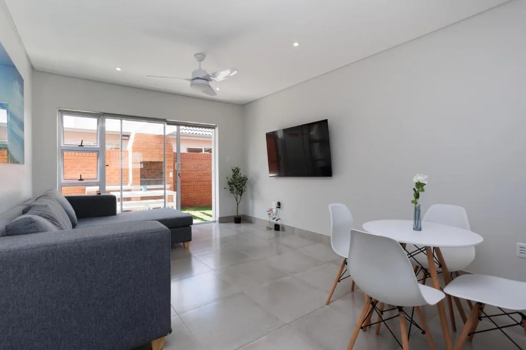 Modern living room with gray sofa, wall-mounted TV, and dining area