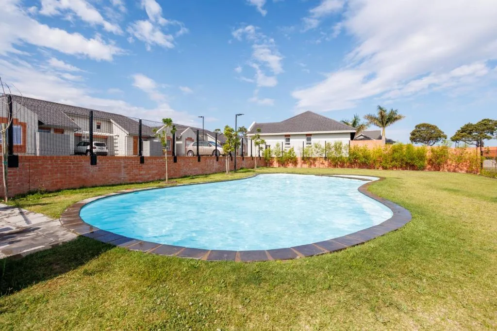 Curved swimming pool with bright blue water surrounded by manicured lawn