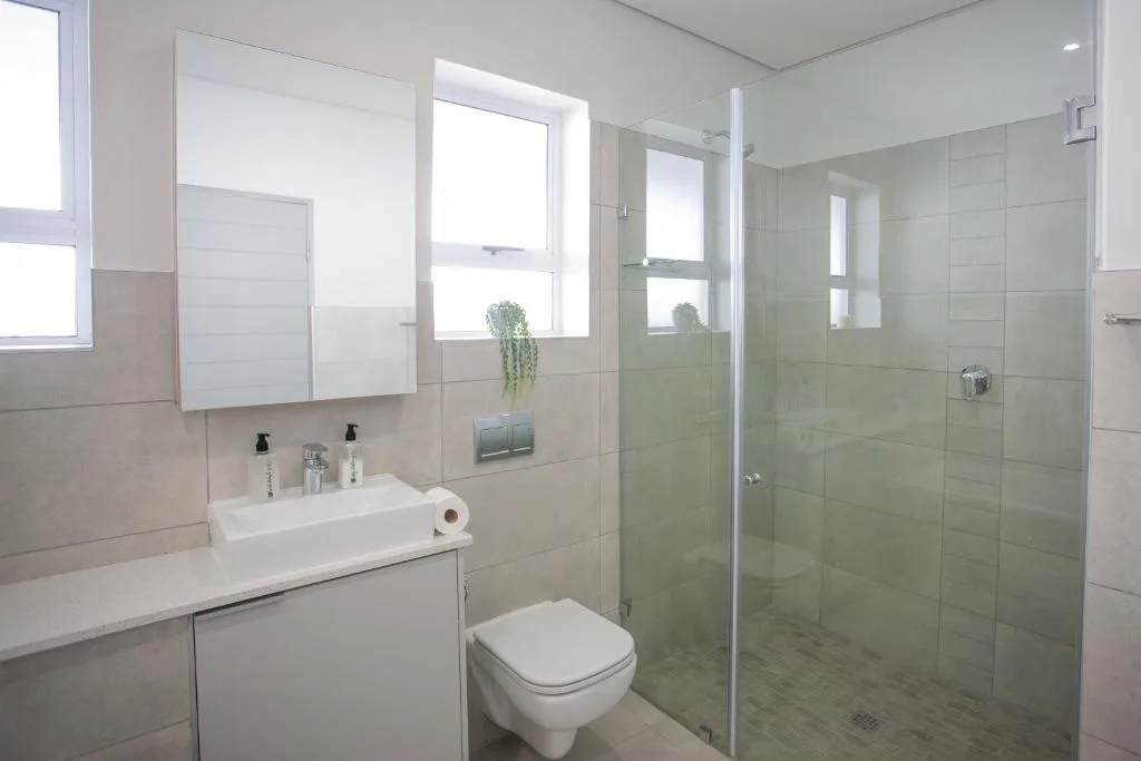Modern bathroom with glass shower enclosure, vanity sink, and toilet