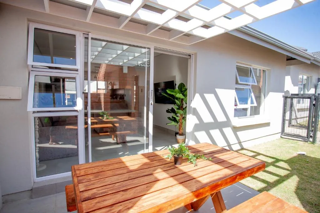 Wooden deck with potted plants overlooking garden and modern house