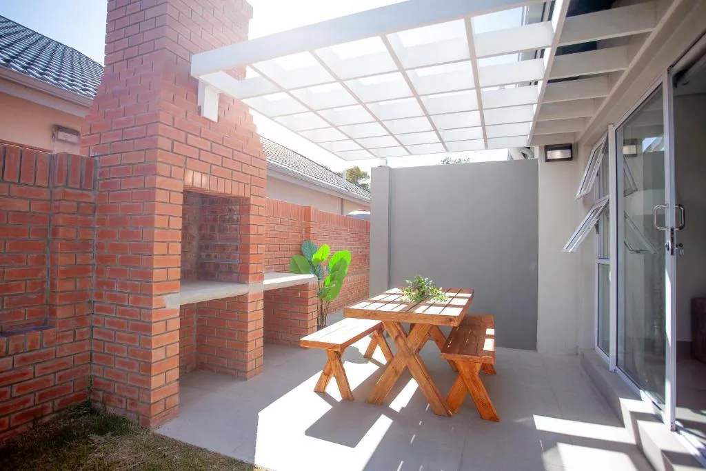 Covered patio with wooden picnic table and brick braai area